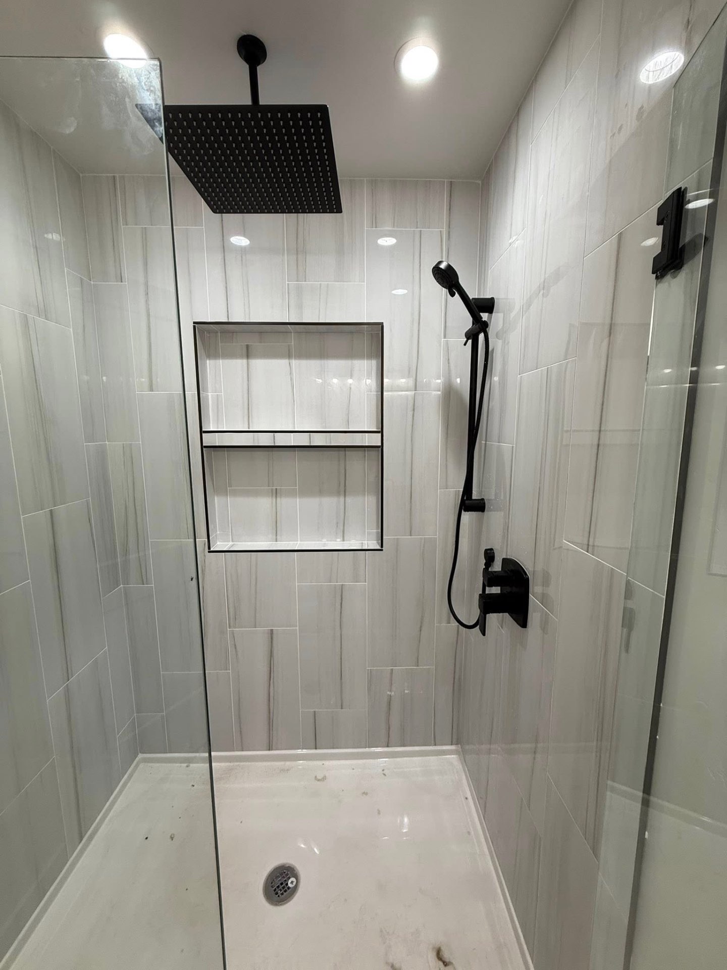 Modern walk-in shower with marble tile and matte black rain head