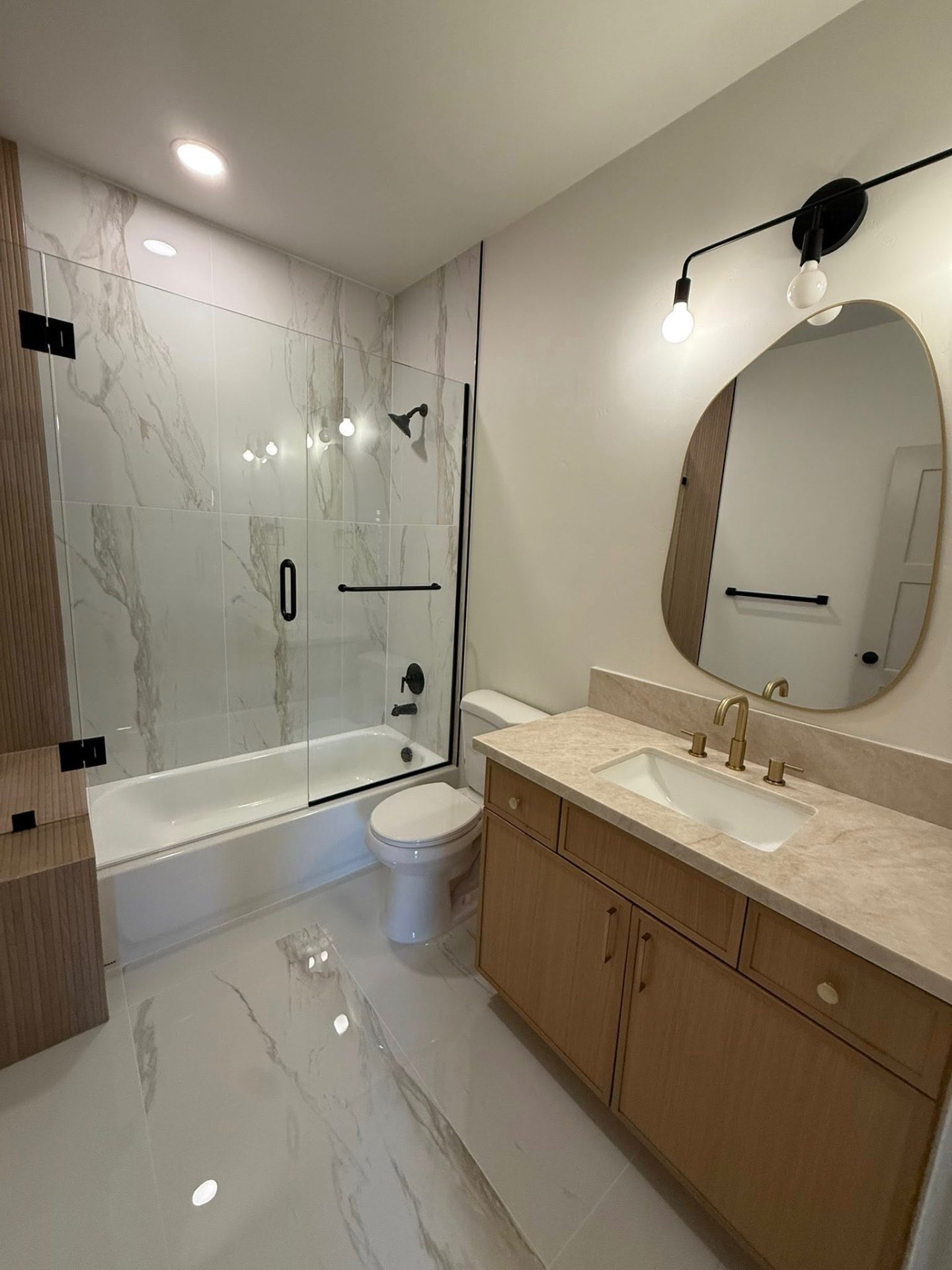 Modern guest bath remodel with marble tile and brass fixtures